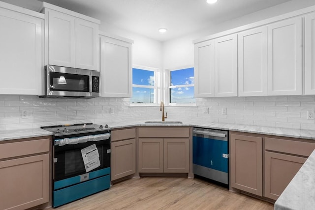 kitchen featuring tasteful backsplash, sink, white cabinets, and appliances with stainless steel finishes