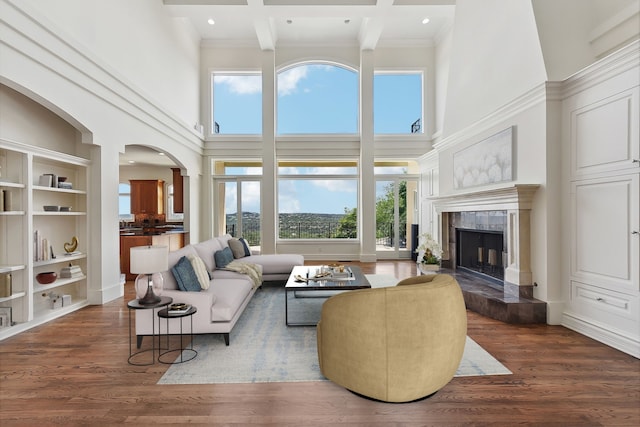 living room with a high ceiling, a tile fireplace, beam ceiling, and dark hardwood / wood-style flooring