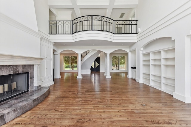 unfurnished living room featuring a high ceiling, decorative columns, and a healthy amount of sunlight