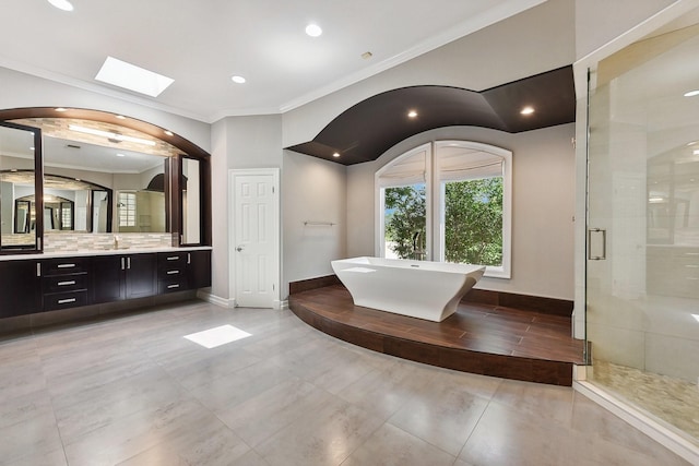 bathroom featuring a skylight, crown molding, vanity, tasteful backsplash, and shower with separate bathtub