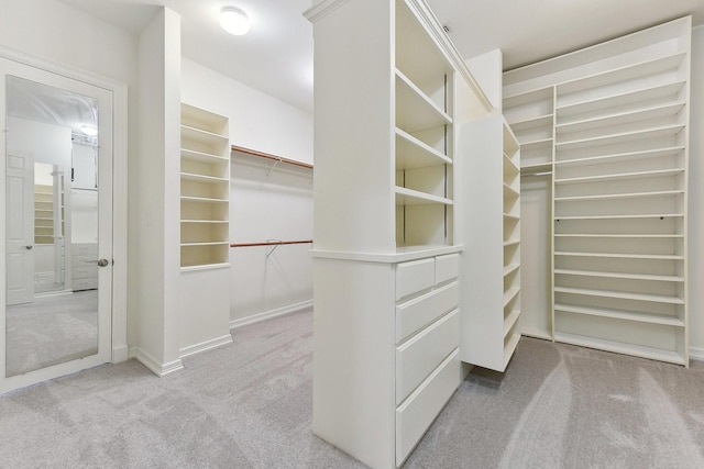 walk in closet featuring light colored carpet