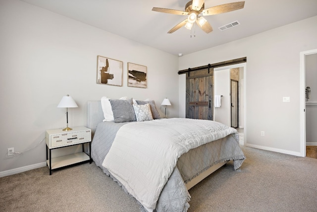 carpeted bedroom featuring a barn door and ceiling fan