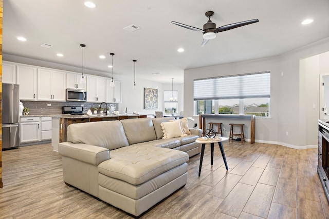 living room featuring ceiling fan, light wood-type flooring, and sink