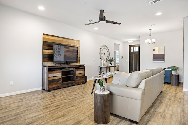 living room with ceiling fan with notable chandelier and light hardwood / wood-style flooring