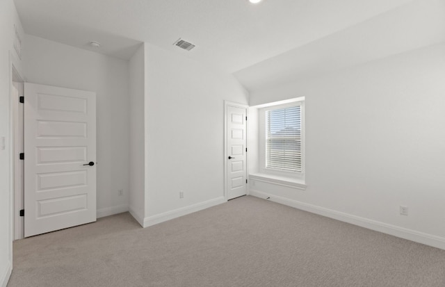 spare room featuring vaulted ceiling and light colored carpet