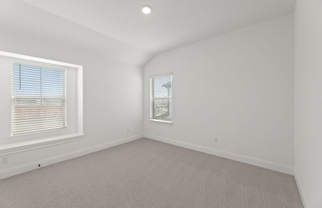 carpeted empty room featuring vaulted ceiling