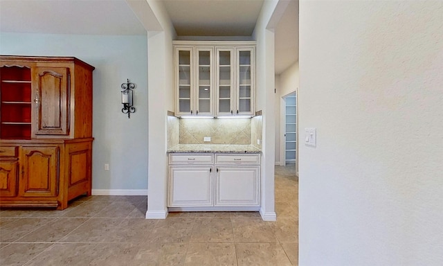 bar with light tile patterned flooring, light stone countertops, and backsplash