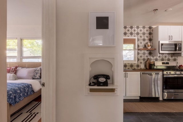 kitchen featuring stainless steel appliances, plenty of natural light, dark tile patterned floors, and white cabinets