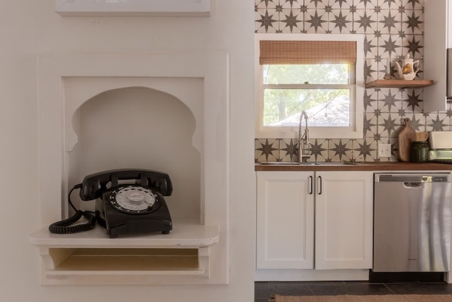 interior space featuring sink, dark tile patterned floors, white cabinetry, tasteful backsplash, and stainless steel dishwasher