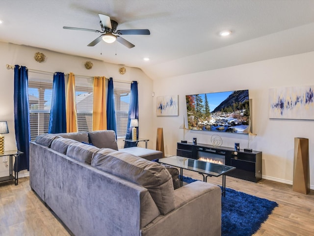 living room featuring ceiling fan, light hardwood / wood-style floors, and lofted ceiling