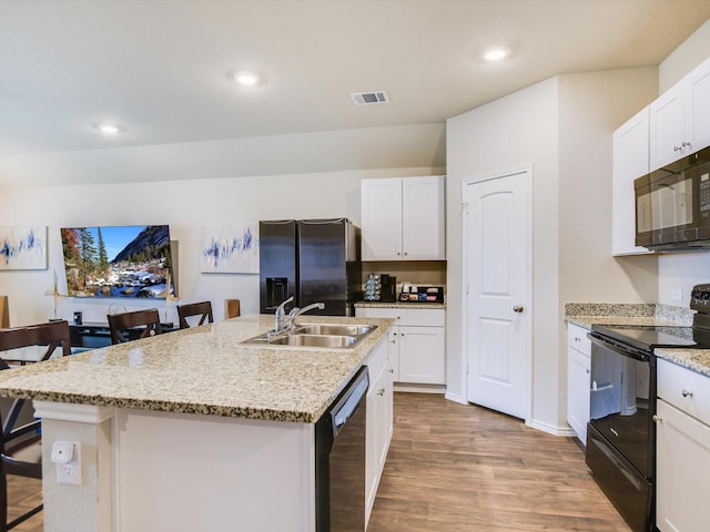 kitchen with sink, black appliances, white cabinets, and an island with sink