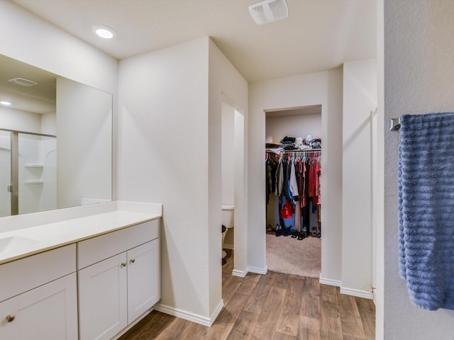 bathroom with wood-type flooring, walk in shower, and vanity