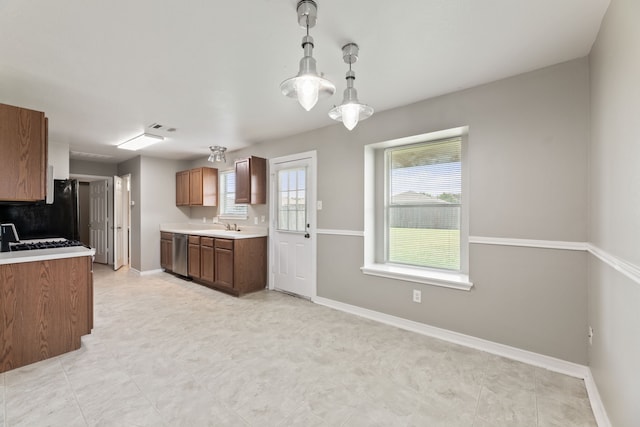 kitchen featuring decorative light fixtures, sink, stainless steel dishwasher, and black fridge