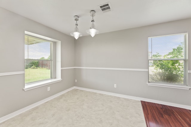 empty room featuring plenty of natural light, light tile patterned floors, and an inviting chandelier