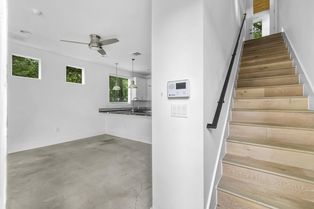 stairs featuring concrete floors, sink, and ceiling fan