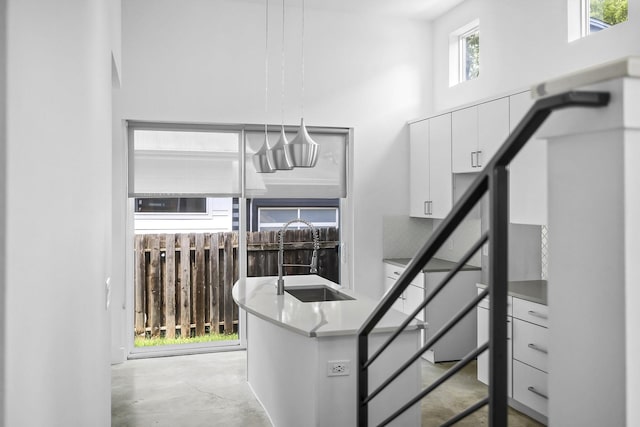 staircase with a high ceiling, sink, and concrete flooring