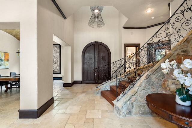 foyer featuring crown molding and a towering ceiling