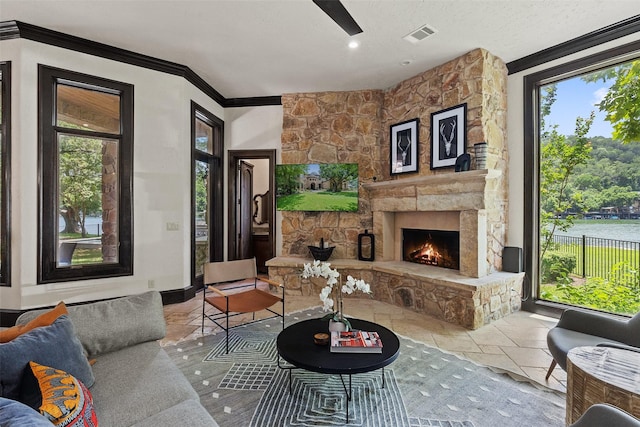 living room featuring crown molding, a stone fireplace, a textured ceiling, and a water view