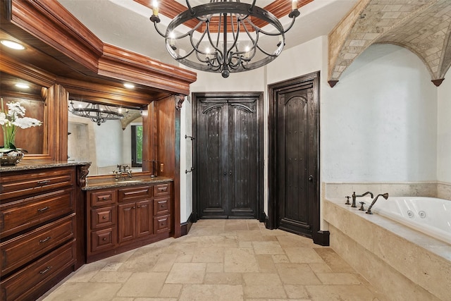 bathroom featuring a relaxing tiled tub, vanity, and an inviting chandelier