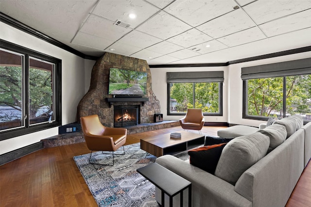 living room featuring a healthy amount of sunlight, a fireplace, ornamental molding, and wood-type flooring