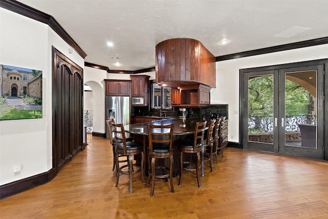 dining room featuring sink, crown molding, french doors, and light wood-type flooring