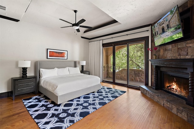 bedroom with a fireplace, wood-type flooring, access to outside, and ceiling fan