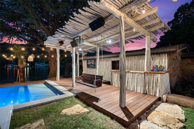 pool at dusk featuring a wooden deck