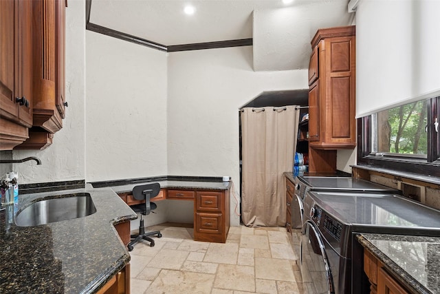 kitchen with crown molding, washing machine and clothes dryer, dark stone counters, and sink