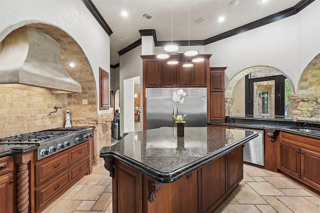 kitchen with crown molding, stainless steel appliances, a kitchen island, and dark stone counters