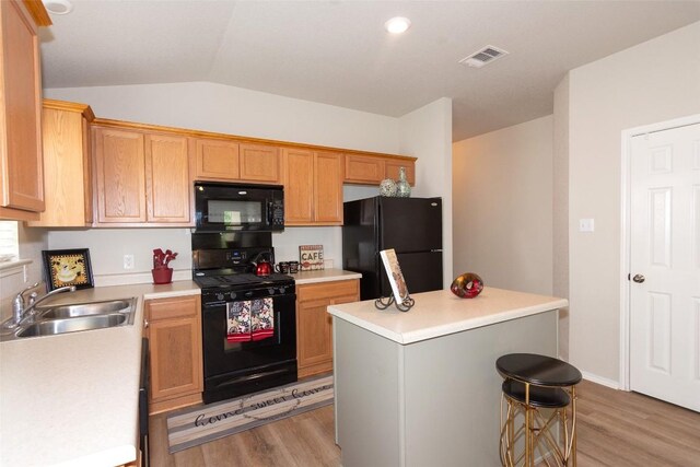 kitchen with black appliances, sink, light hardwood / wood-style floors, a kitchen island, and lofted ceiling