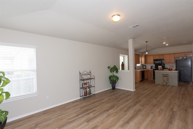 living room with light hardwood / wood-style floors and vaulted ceiling