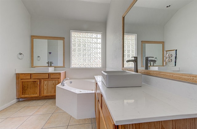 bathroom featuring vaulted ceiling, vanity, a washtub, and tile patterned floors