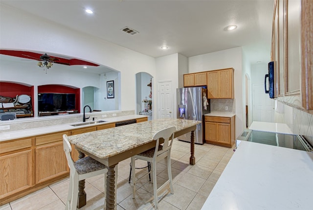 kitchen featuring light tile patterned flooring, tasteful backsplash, ceiling fan, stainless steel refrigerator with ice dispenser, and sink