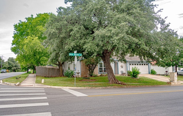 view of property hidden behind natural elements with a garage and a front lawn