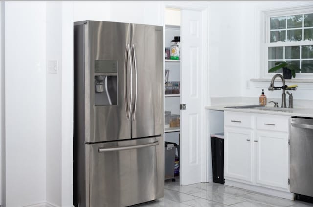 kitchen featuring appliances with stainless steel finishes, sink, and white cabinets