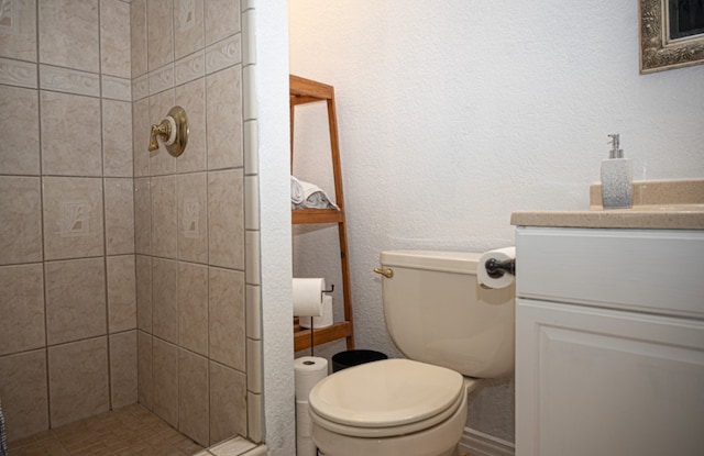 bathroom featuring vanity, a tile shower, and toilet