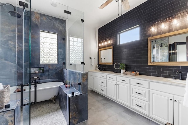 bathroom with a ceiling fan, double vanity, a freestanding tub, a sink, and decorative backsplash