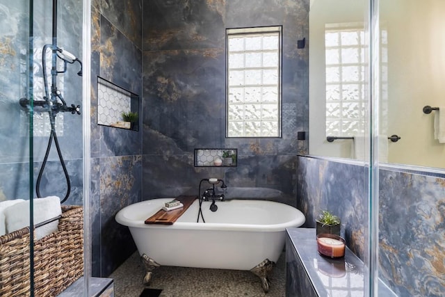 bathroom featuring walk in shower, a freestanding tub, and tile walls