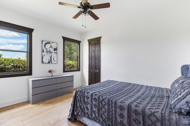 bedroom featuring light wood-style flooring, a ceiling fan, and baseboards