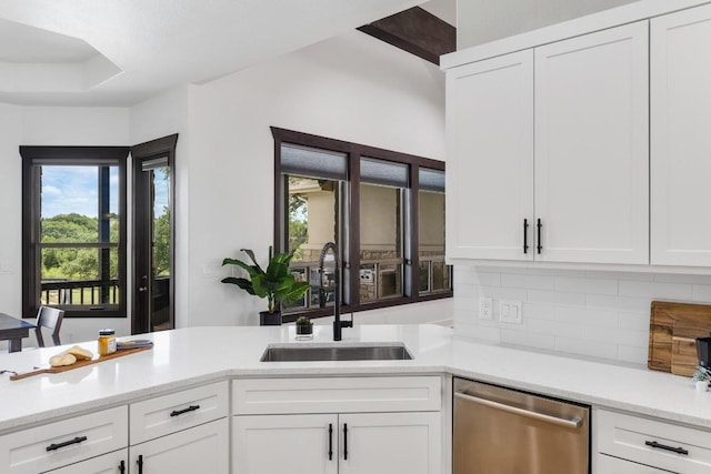 kitchen with dishwasher, decorative backsplash, white cabinets, and a sink