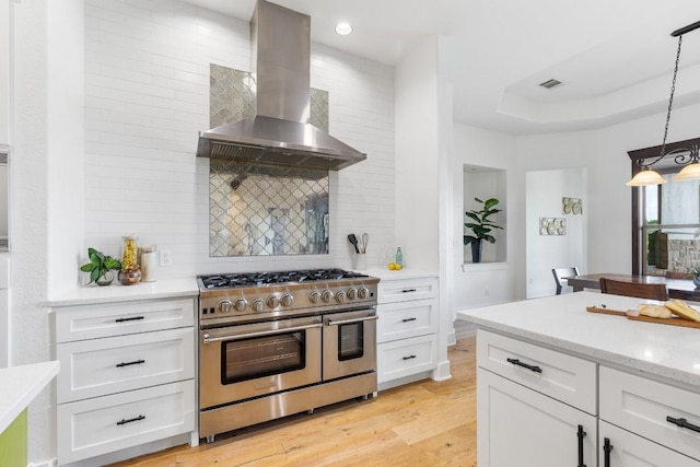 kitchen featuring ventilation hood, light wood finished floors, range with two ovens, white cabinetry, and backsplash