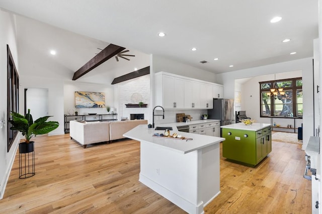 kitchen with a sink, a center island, freestanding refrigerator, a stone fireplace, and light countertops