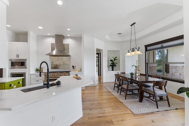 kitchen with backsplash, ventilation hood, light countertops, appliances with stainless steel finishes, and a sink