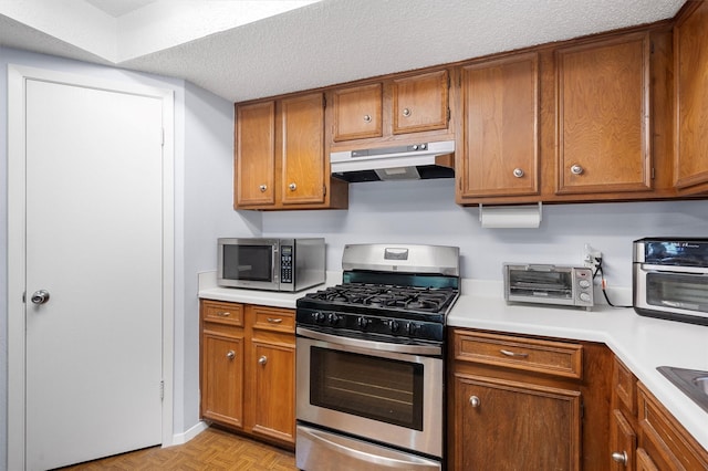 kitchen with light parquet floors, appliances with stainless steel finishes, a textured ceiling, and sink