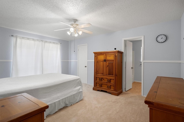 bedroom with ceiling fan, a textured ceiling, and light carpet