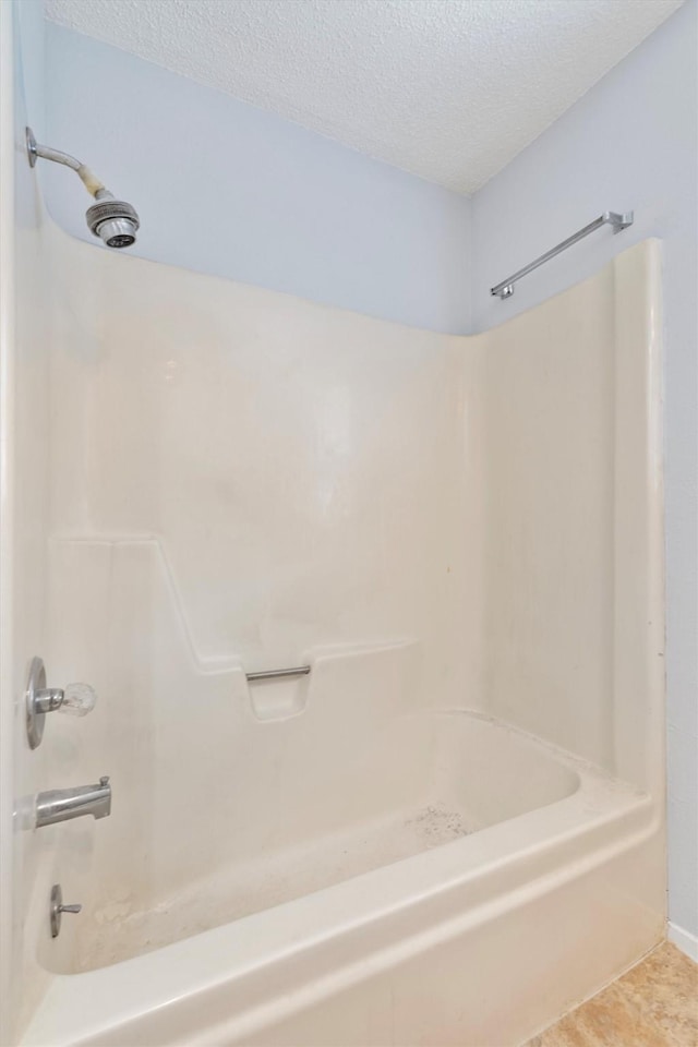 bathroom featuring a textured ceiling, tile patterned floors, and washtub / shower combination