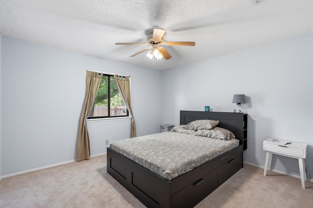 bedroom featuring ceiling fan, a textured ceiling, and light carpet