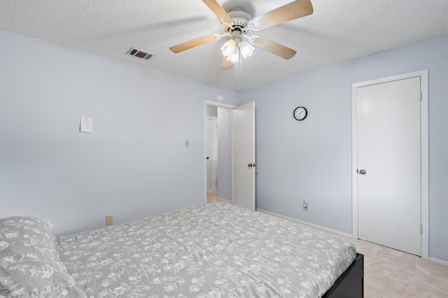 carpeted bedroom with ceiling fan and a textured ceiling