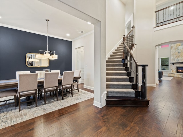 3417 Flat Iron Ct, Leander, TX 78641 - dining space featuring hardwood / wood-style floors, stairway, crown molding, a chandelier, and a fireplace
