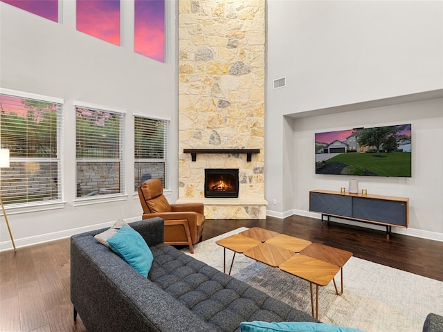 living area featuring visible vents, a fireplace, baseboards, and wood finished floors